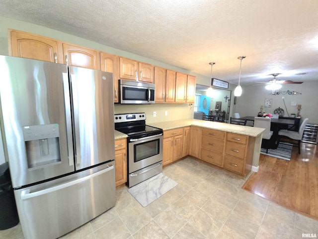 1401 Glopen Rd, Carbondale, IL 62901 - kitchen with appliances with stainless steel finishes, light countertops, a peninsula, light brown cabinets, and a textured ceiling