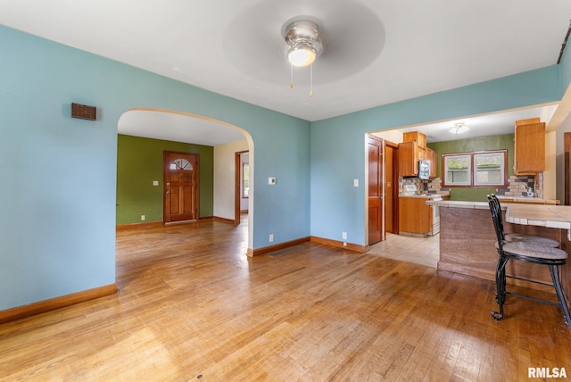 204 E Main St, Joy, IL 61260 - kitchen with arched walkways, white range oven, stainless steel microwave, brown cabinets, and light wood finished floors