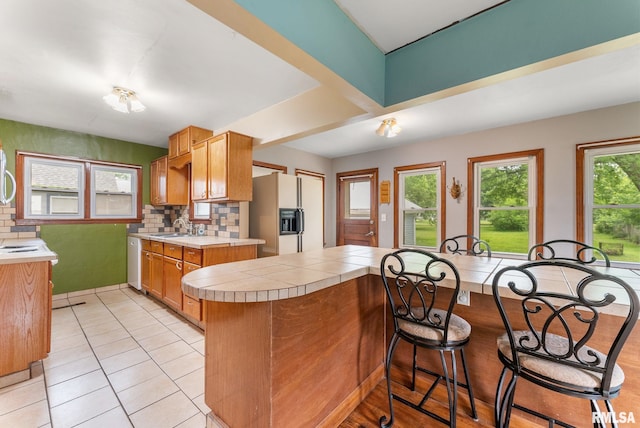 204 E Main St, Joy, IL 61260 - kitchen with white appliances, light tile patterned floors, backsplash, a kitchen bar, and a peninsula