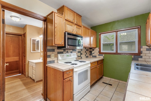 204 E Main St, Joy, IL 61260 - kitchen with white electric range, stainless steel microwave, tile counters, and decorative backsplash