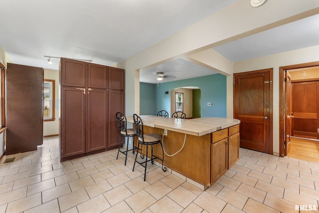 204 E Main St, Joy, IL 61260 - kitchen featuring a kitchen breakfast bar, tile counters, a peninsula, arched walkways, and ceiling fan