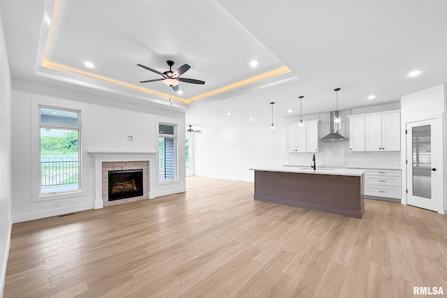 1354 Heights Ct, Bettendorf, IA 52722 - unfurnished living room featuring a tray ceiling, ceiling fan, light wood finished floors, recessed lighting, and a stone fireplace