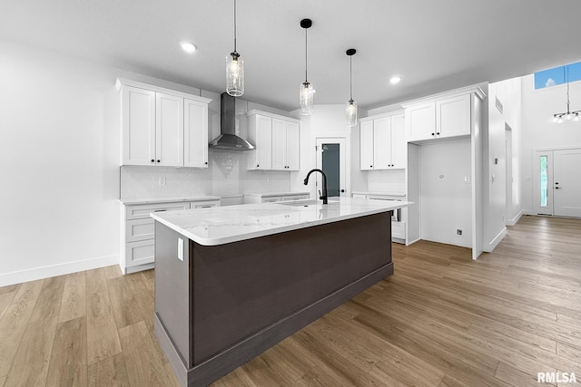 1354 Heights Ct, Bettendorf, IA 52722 - kitchen featuring wall chimney exhaust hood, a center island with sink, light wood-type flooring, white cabinetry, and recessed lighting