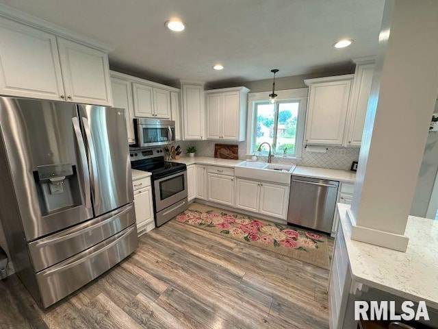 1144 Brookview Dr, De Witt, IA 52742 - kitchen with stainless steel appliances, light wood-style floors, decorative backsplash, white cabinetry, and recessed lighting