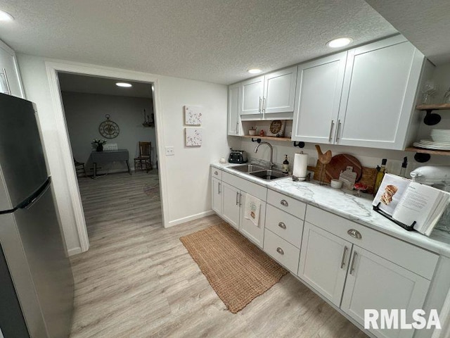 1144 Brookview Dr, De Witt, IA 52742 - kitchen with open shelves, freestanding refrigerator, light wood-style flooring, a textured ceiling, and white cabinets
