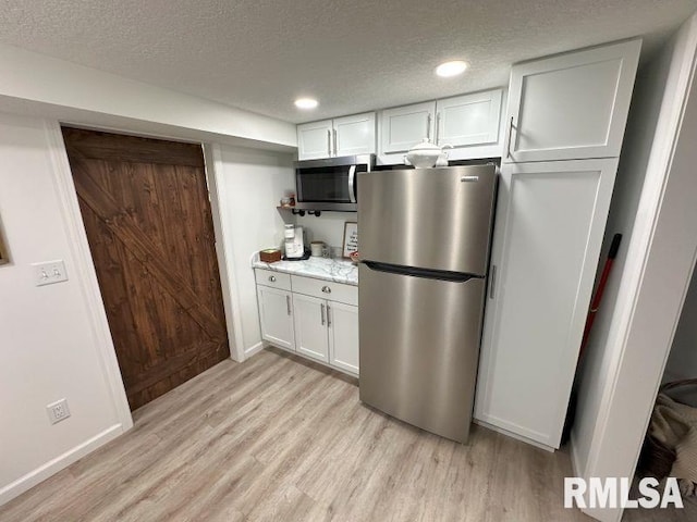 1144 Brookview Dr, De Witt, IA 52742 - kitchen with appliances with stainless steel finishes, light wood finished floors, a textured ceiling, light countertops, and white cabinets
