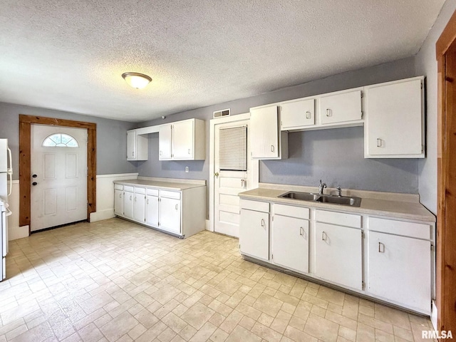 511 Fulton St, Grand Mound, IA 52751 - kitchen featuring light countertops, white cabinetry, brick patterned flooring, a textured ceiling, and freestanding refrigerator