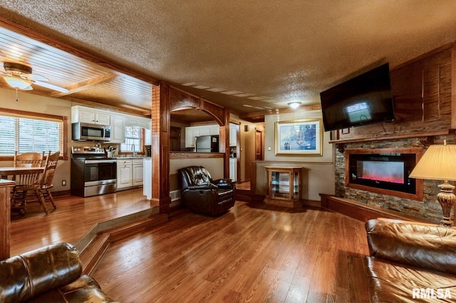 1445 Lawrence Ave, Camanche, IA 52730 - living room with a glass covered fireplace, hardwood / wood-style floors, a textured ceiling, and a ceiling fan