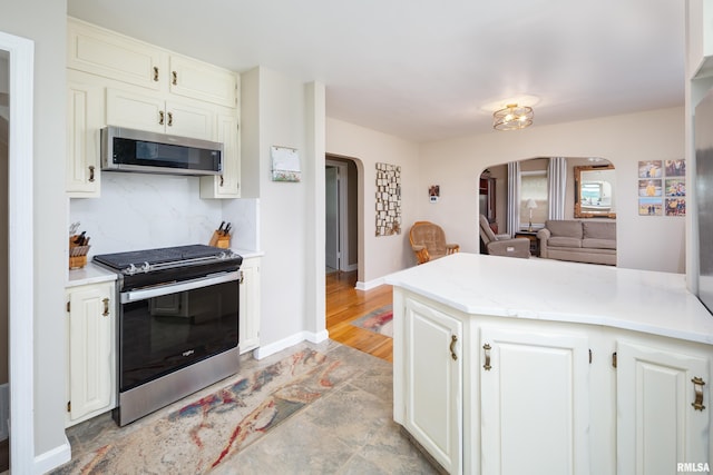 13524 US Route 67, Milan, IL 61264 - kitchen featuring stainless steel appliances, arched walkways, light countertops, tasteful backsplash, and white cabinets