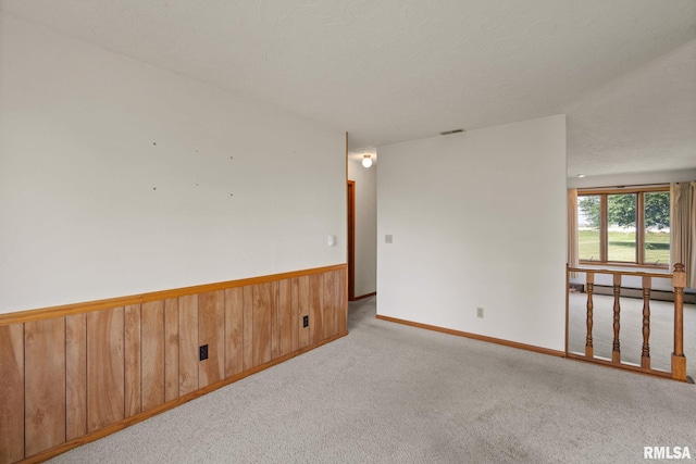 20425 20th Ave, Stockton, IA 52769 - unfurnished room featuring carpet, wooden walls, a baseboard radiator, and wainscoting