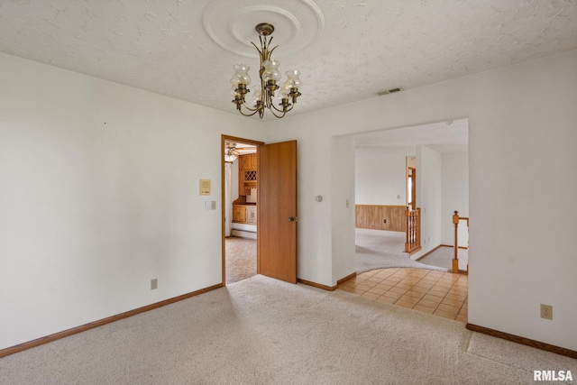 20425 20th Ave, Stockton, IA 52769 - empty room featuring carpet, a chandelier, a textured ceiling, and tile patterned flooring