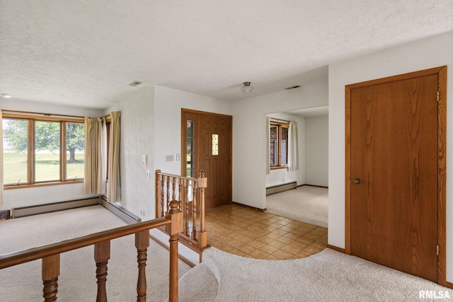 20425 20th Ave, Stockton, IA 52769 - entrance foyer featuring a baseboard heating unit, light colored carpet, a textured ceiling, light tile patterned flooring, and a baseboard radiator