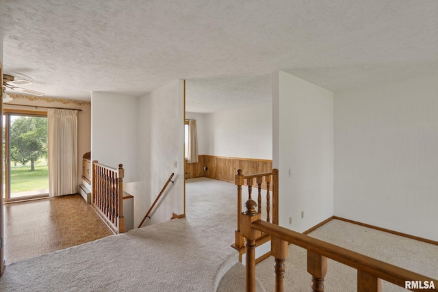 20425 20th Ave, Stockton, IA 52769 - hallway featuring an upstairs landing, a textured ceiling, carpet, and wooden walls