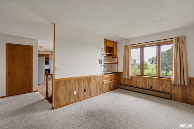 20425 20th Ave, Stockton, IA 52769 - spare room featuring baseboard heating, wooden walls, a textured ceiling, carpet floors, and wainscoting