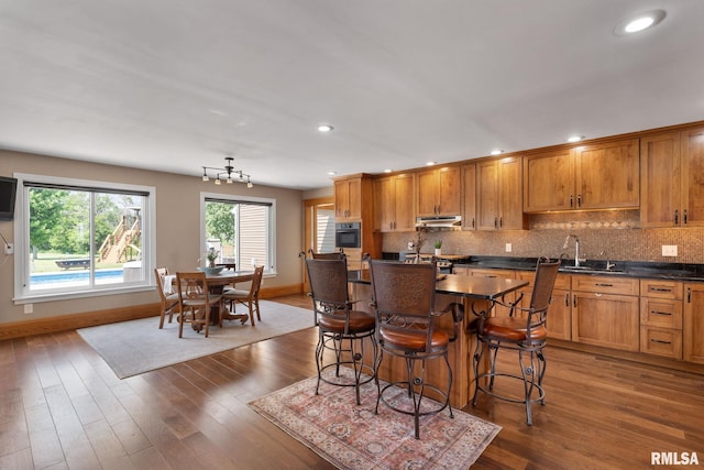 3473 270th St, De Witt, IA 52742 - kitchen featuring under cabinet range hood, dark countertops, recessed lighting, range, and decorative backsplash