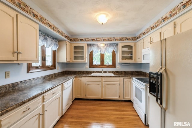 1031 15th Pl, Camanche, IA 52730 - kitchen featuring white appliances, dark countertops, glass insert cabinets, and light wood-type flooring
