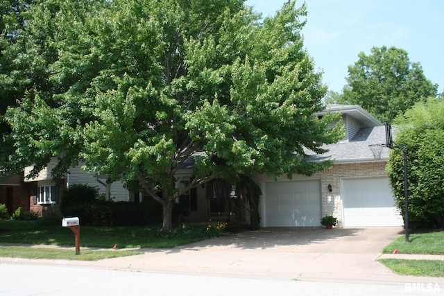 4145 Aspen Hills Dr, Bettendorf, IA 52722 - view of property hidden behind natural elements featuring concrete driveway, brick siding, an attached garage, and a front yard