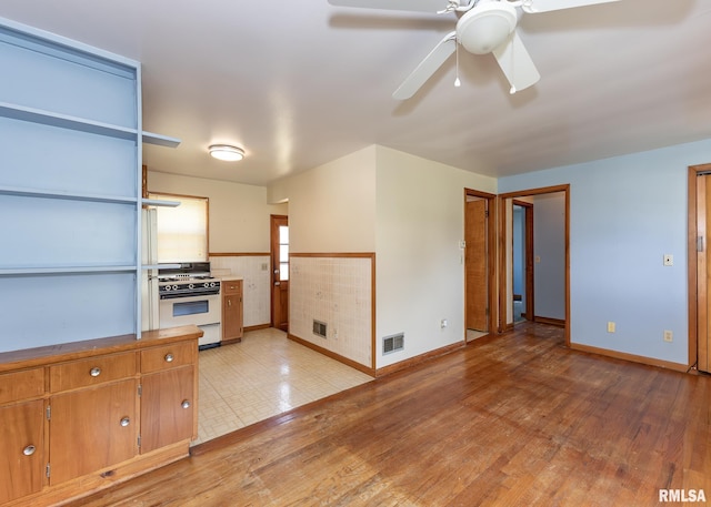 430 10th Pl, Camanche, IA 52730 - kitchen with gas range gas stove, a ceiling fan, light wood-style floors, and brown cabinetry