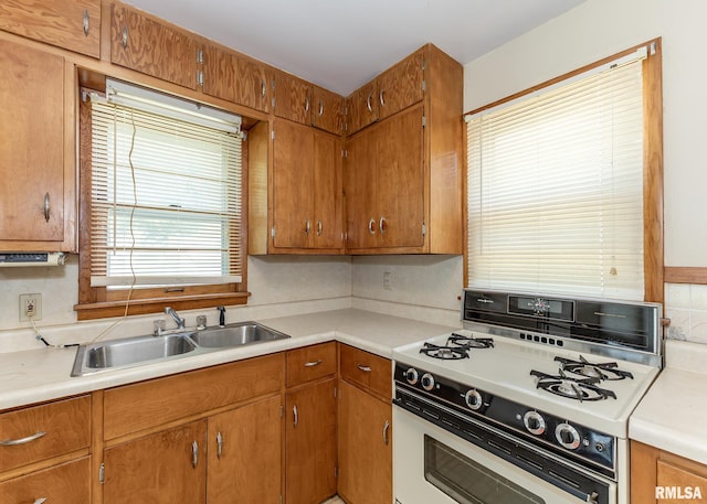430 10th Pl, Camanche, IA 52730 - kitchen featuring white range with gas cooktop, light countertops, brown cabinets, and decorative backsplash
