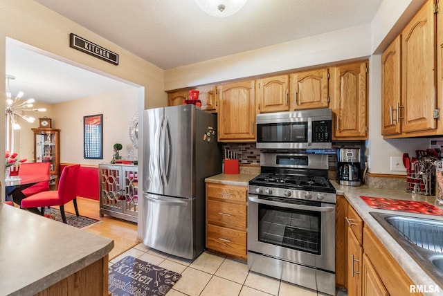 5903 36th Avenue Ct Unit 19, Moline, IL 61265 - kitchen with appliances with stainless steel finishes, light tile patterned floors, backsplash, a chandelier, and light countertops