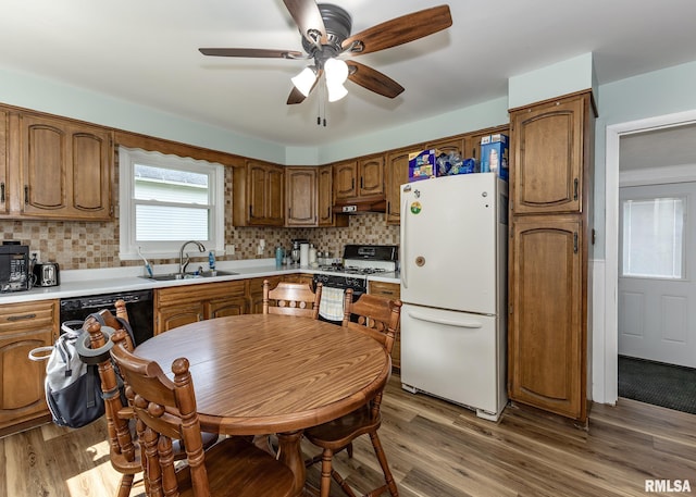 3020 Cleveland St, Clinton, IA 52732 - kitchen with freestanding refrigerator, range with gas stovetop, under cabinet range hood, and wood finished floors