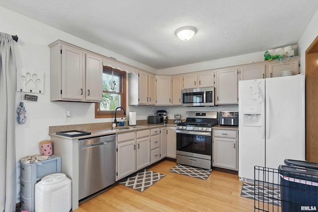 1426 W 48th St, Davenport, IA 52806 - kitchen featuring appliances with stainless steel finishes, light wood finished floors, and a textured ceiling