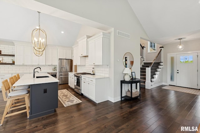 6925 Grover Sta, Bettendorf, IA 52722 - kitchen featuring stainless steel appliances, high vaulted ceiling, a chandelier, tasteful backsplash, and white cabinets