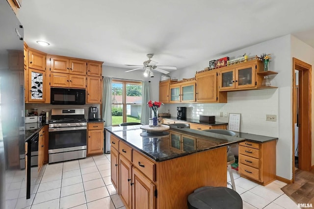 1020 Brown St, Bettendorf, IA 52722 - kitchen with stainless steel range with gas stovetop, black microwave, decorative backsplash, a ceiling fan, and light tile patterned flooring