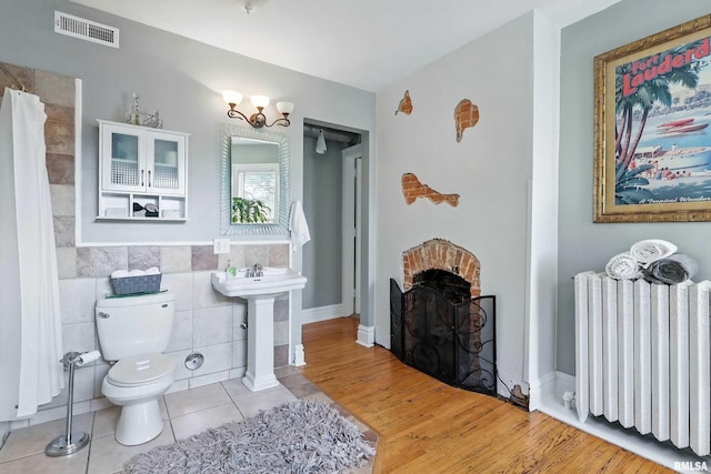 1703 20th St, Rock Island, IL 61201 - full bath featuring radiator, tile walls, tile patterned floors, and a shower with curtain