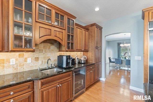 5985 Eagle Ridge Rd, Bettendorf, IA 52722 - kitchen with wine cooler, brown cabinets, a chandelier, tasteful backsplash, and light wood finished floors