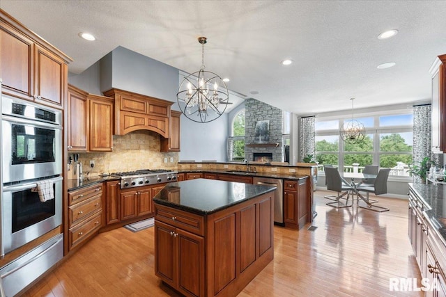 5985 Eagle Ridge Rd, Bettendorf, IA 52722 - kitchen with stainless steel appliances, a warming drawer, a chandelier, a stone fireplace, and a peninsula