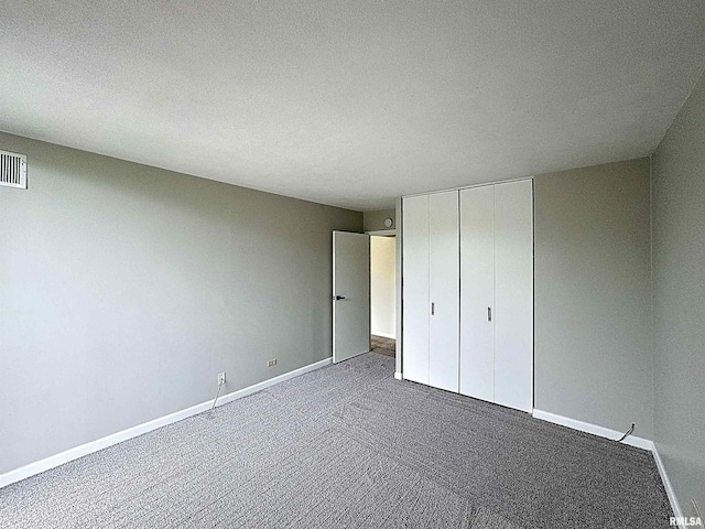 1800 7th St Unit 6D, East Moline, IL 61244 - unfurnished bedroom featuring dark carpet, a closet, and a textured ceiling