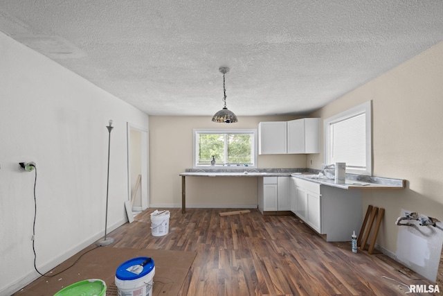 1312 Farnam St, Davenport, IA 52803 - kitchen featuring dark wood finished floors, white cabinets, light countertops, pendant lighting, and a textured ceiling