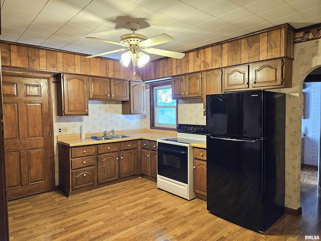 320 W 4th St, Wilton, IA 52778 - kitchen featuring freestanding refrigerator, range with electric stovetop, wallpapered walls, light wood-style floors, and a ceiling fan
