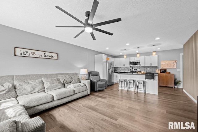 3307 Clover Hills Dr, Bettendorf, IA 52722 - living area featuring a ceiling fan, light wood-style flooring, a textured ceiling, and recessed lighting