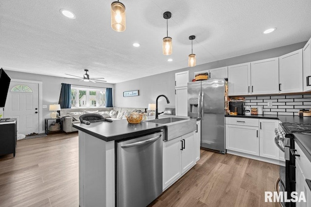 3307 Clover Hills Dr, Bettendorf, IA 52722 - kitchen featuring stainless steel appliances, dark countertops, a textured ceiling, open floor plan, and white cabinetry
