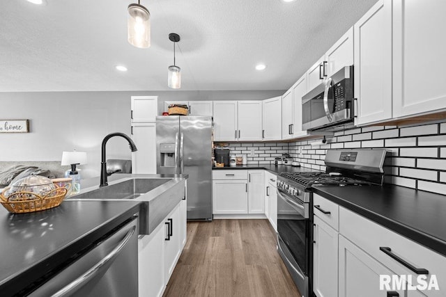 3307 Clover Hills Dr, Bettendorf, IA 52722 - kitchen featuring appliances with stainless steel finishes, dark countertops, wood finished floors, a textured ceiling, and white cabinets