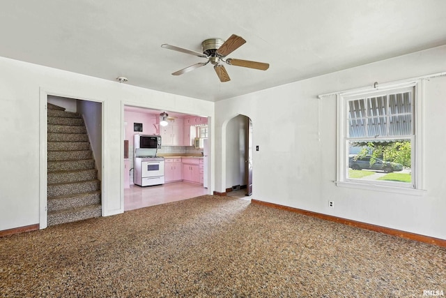 2348 24 1/2 St, Rock Island, IL 61201 - unfurnished living room featuring arched walkways, ceiling fan, light carpet, and stairway
