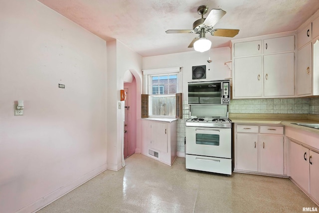 2348 24 1/2 St, Rock Island, IL 61201 - kitchen with black microwave, white range with gas cooktop, arched walkways, decorative backsplash, and light countertops