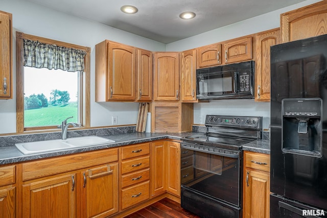 4460 160th St, Clinton, IA 52732 - kitchen featuring black appliances, dark countertops, dark wood-style floors, recessed lighting, and brown cabinetry