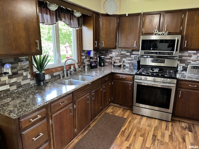 101 E 6th St, Sherrard, IL 61281 - kitchen with appliances with stainless steel finishes, decorative backsplash, dark stone countertops, light wood-style floors, and dark brown cabinets