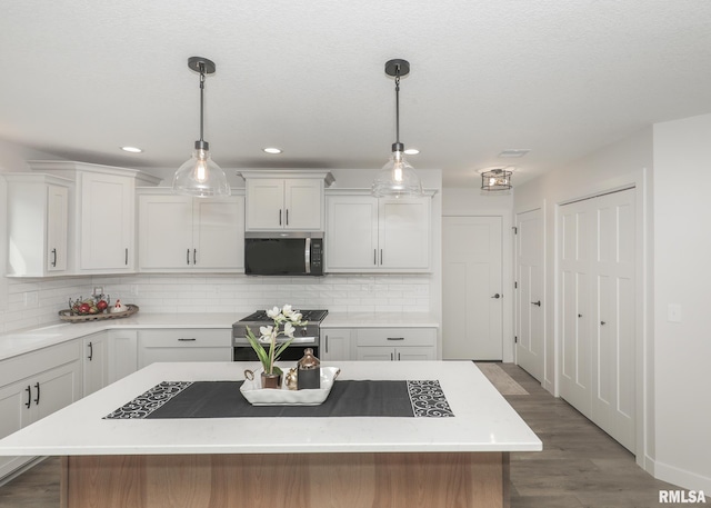 624 Rock Point Rd, Colona, IL 61241 - kitchen featuring stainless steel appliances, light countertops, a center island, wood finished floors, and decorative backsplash