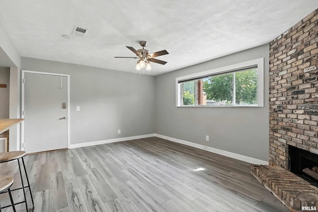 3045 4th St Unit 1, Moline, IL 61265 - unfurnished living room featuring a ceiling fan, wood finished floors, and a brick fireplace