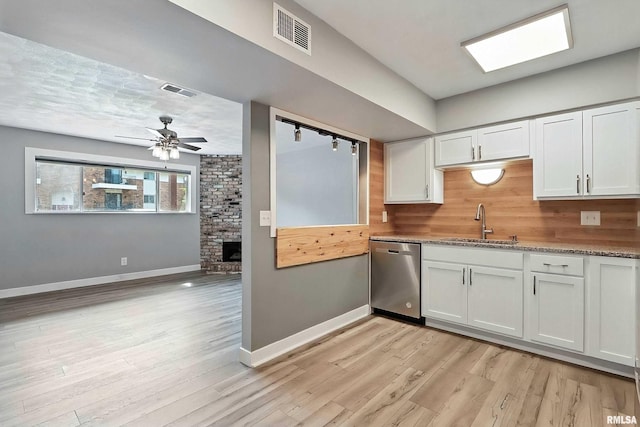 3045 4th St Unit 1, Moline, IL 61265 - kitchen with stainless steel dishwasher, a fireplace, a ceiling fan, white cabinets, and light wood-style floors