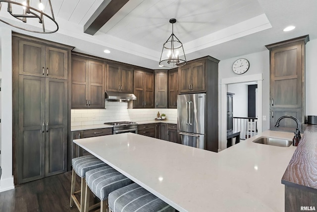 6250 Whispering Hill Ct, Bettendorf, IA 52722 - kitchen featuring high quality appliances, under cabinet range hood, a peninsula, tasteful backsplash, and a chandelier