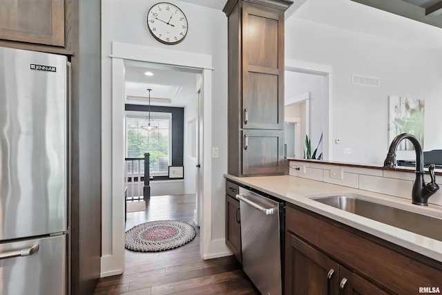 6250 Whispering Hill Ct, Bettendorf, IA 52722 - kitchen with stainless steel appliances, dark wood-style floors, light countertops, a raised ceiling, and dark brown cabinetry