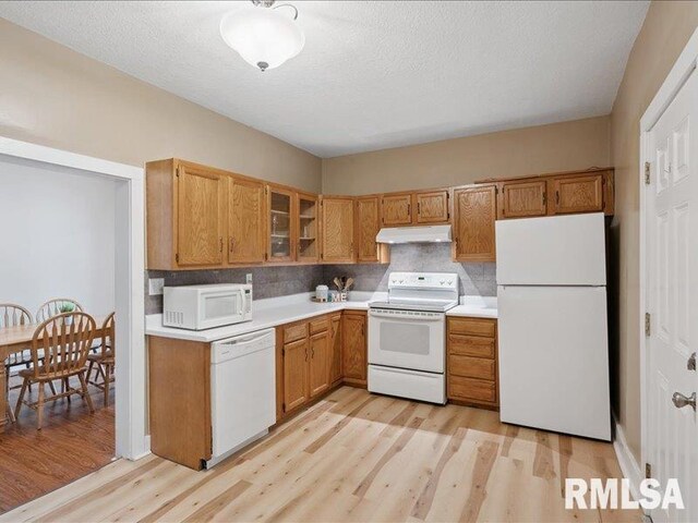 821 42nd St, Rock Island, IL 61201 - kitchen with white appliances, under cabinet range hood, light wood-style floors, light countertops, and brown cabinetry