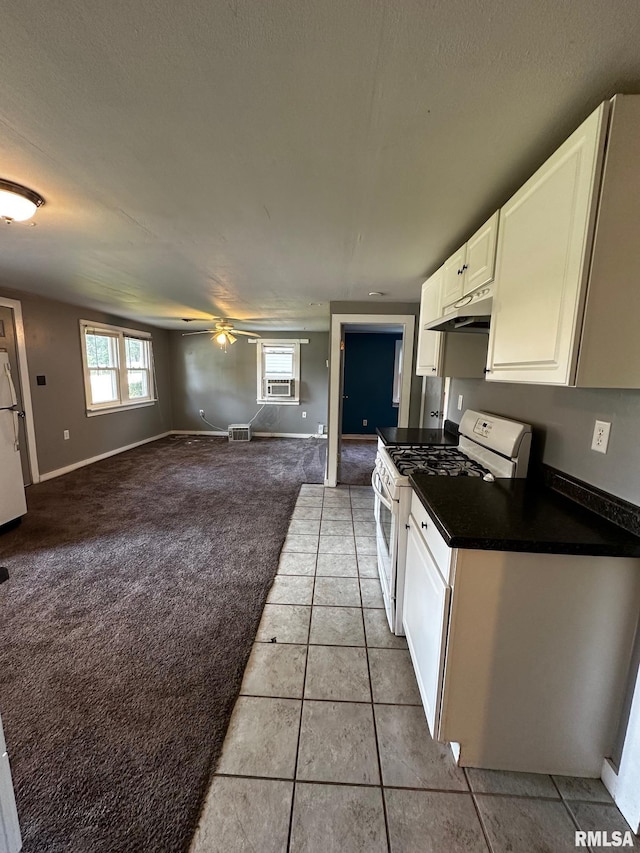920 5th St, Colona, IL 61241 - kitchen featuring white range with gas cooktop, under cabinet range hood, dark countertops, white cabinets, and ceiling fan