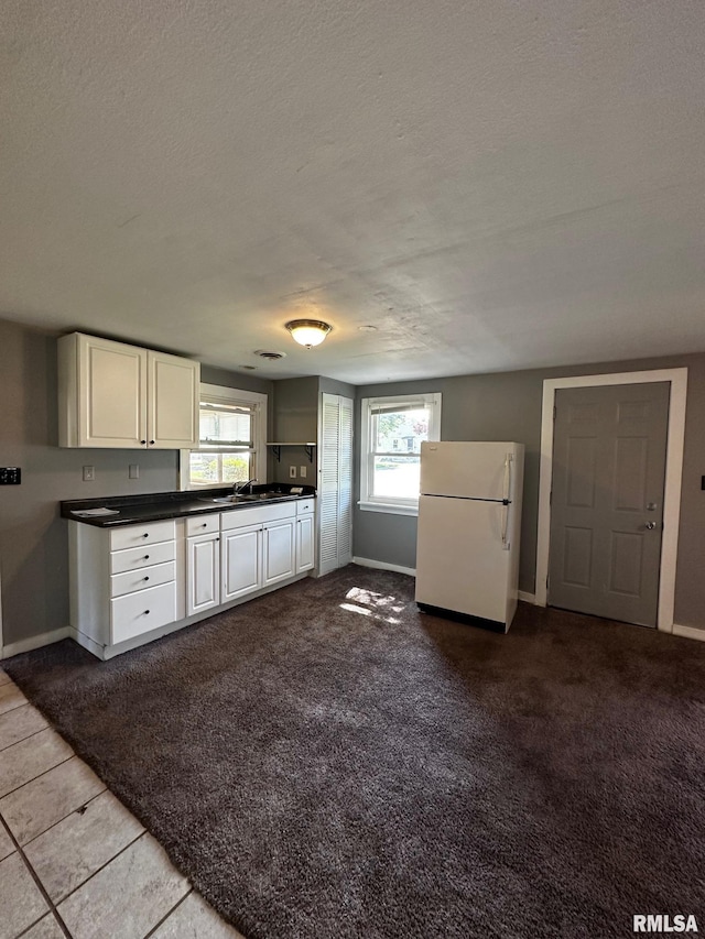 920 5th St, Colona, IL 61241 - kitchen with freestanding refrigerator, dark countertops, a textured ceiling, and white cabinetry