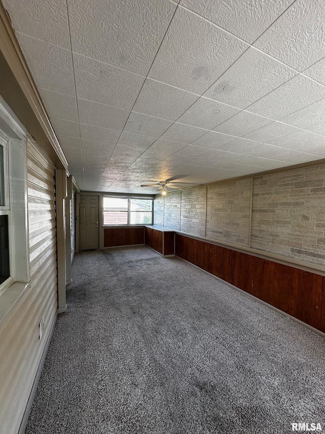 920 5th St, Colona, IL 61241 - carpeted empty room with wood walls and a ceiling fan